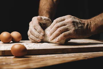 Beautiful and strong men's hands knead the dough from which they will then make bread, pasta or...