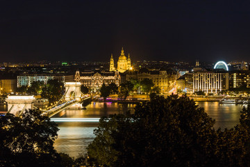 Fototapeta na wymiar Budapest urban scape with Devil's Wheel and the illuminated Chain Bridge across the Danube River by night.