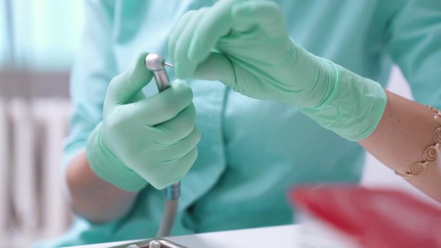 Dentist hands changes borer on the dental drill machine. Dentist's hands with blue gloves working with dental drill in dental office. Close up, selective focus