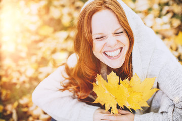 Portrait einer freundlichen Rothaarigen Frau im Herbst mit Ahornblättern