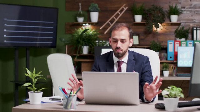 Large shot of businessman in formal wearing having a video talk using his laptop