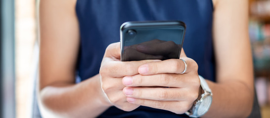 Young casual Businesswoman holding and using smartphone for sms messages, hipster woman typing touchscreen cell phone in the cafe. business, lifestyle, technology and Social media network concept