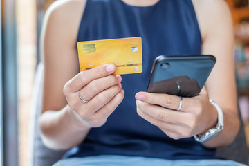 Young casual Business woman holding credit card and using touchscreen smartphone for online shopping while making orders in the cafe.business, lifestyle,technology,ecommerce and online payment concept