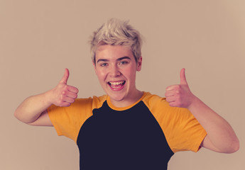 Portrait of handsome transgender teenager making thumbs up gesture feeling happy and successful