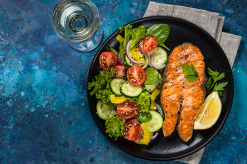 Grilled salmon fish steak with vegetables top view.