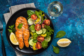 Grilled salmon fish steak with vegetables top view.