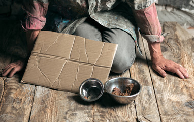 Male beggar hands seeking food or money with coins' tin from human kindness on the wooden floor at...