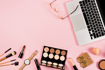 top view of laptop, accessories and decorative cosmetics on pink