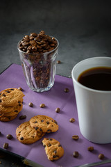 Black hot coffee with steam in a white coffee cup, placed on a book with cookies  with a loft-style background.