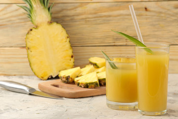 Pineapple juice in a glass and pieces of fresh pineapple on a natural wooden background. summer. fruits.