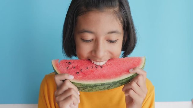 Portrait picture face of asian little girl looking watermelon slice on blue background. A cute girl so excited.
