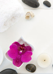 Fototapeta na wymiar Spa setting with pink orchids, black stones and bath salts on wood background.