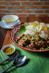 Fried pork rice with garlic, pepper and fried eggs and seasoning sauce on a wooden table