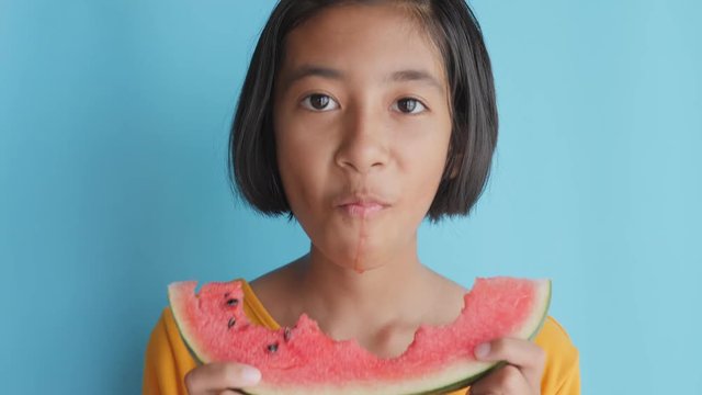 Portrait picture face of asian little girl looking watermelon slice on blue background. A cute girl so excited.
