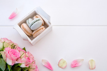 Pink roses and macaron cookies in the basket on white background.