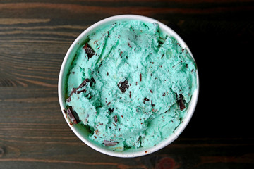 Top View of Mint Chocolate Chip Ice Cream in a Large Cup on Dark Brown Wooden Table 