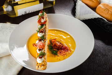 Cream soup, baguette on brown wooden table, served with white wine, copy space