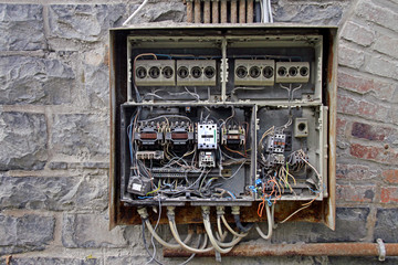 Fototapeta na wymiar Chaotic cables in a fuse box in an abandoned building