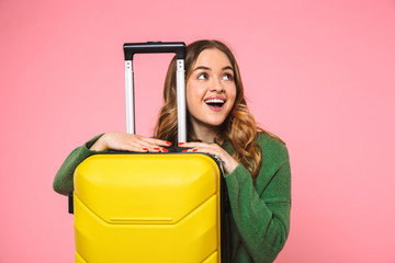 Pleased blonde woman wearing in green sweater posing with baggage