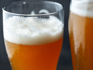 Two glasses of unfiltered cold wheat craft beer on a dark table