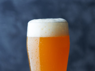Close-up of a glass of cold wheat craft beer of saturated orange color