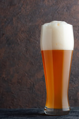 Glass of unfiltered wheat beer on brown concrete background
