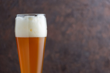 Glass of unfiltered wheat beer on brown concrete background