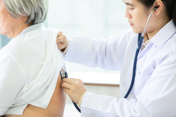 Female physician listening patient’s back through stethoscope,asian doctor or nurse checking...