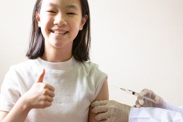  Hand of female doctor with syringe doing injection vaccine,flu,influenza in the shoulder of  little asian girl, nurse injecting,vaccinating child patient,vaccination,medicine,health care concept
