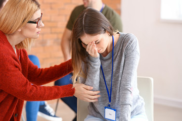 Psychologist calming woman at group therapy session