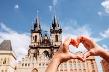 Girl showing heart shape love symbol over cityscape, Tyn Church. Woman making heart shape with...