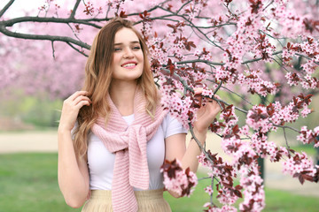 Fototapeta na wymiar Beautiful young woman near blossoming tree on spring day