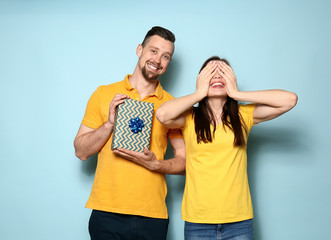 Fototapeta premium Young man greeting his girlfriend on color background