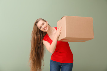 Young woman with cardboard box on color background