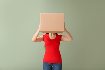 Young woman with cardboard box on color background