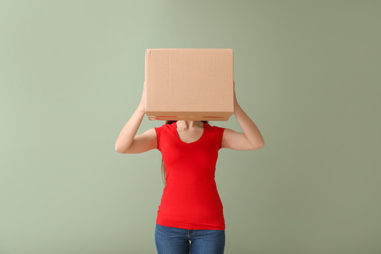 Young woman with cardboard box on color background