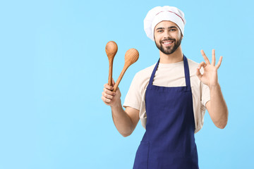 Handsome male chef on color background