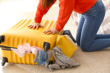 Woman trying to close suitcase with a lot of things. Travel concept