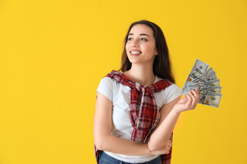 Happy young woman with dollar banknotes on color background