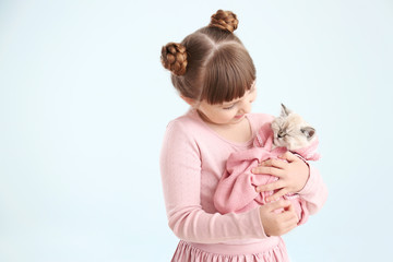 Girl with cute fluffy kitten on light background