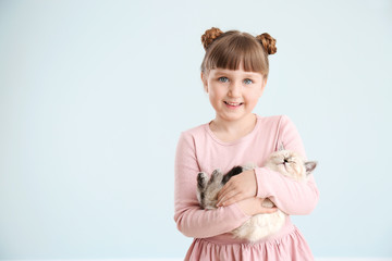 Girl with cute fluffy kitten on light background