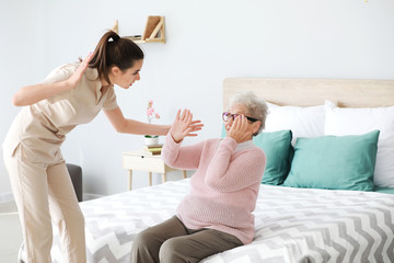 Caregiver mistreating senior woman in nursing home