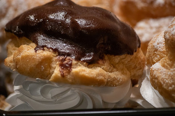 powdered sugar and shiny chocolate cream puffs filled with a swirl of white whipped cream