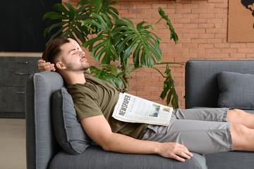 Handsome man with newspaper sleeping at home