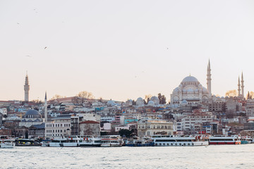 Fototapeta premium Scenic view of Istanbul and the Galata Tower from the Bosphorus Bay, shot on a sunny day. Vintage fishing boats on the coast in Istanbul. Passenger ferry through the Bosphorus