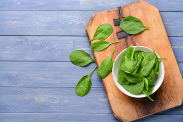 Bowl with fresh spinach on wooden table