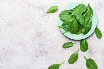 Plate with fresh spinach on grey background