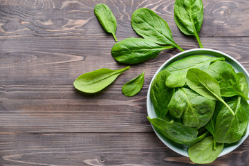Plate with fresh spinach on wooden table