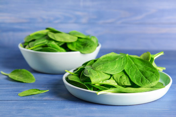 Plate with fresh spinach on color wooden background