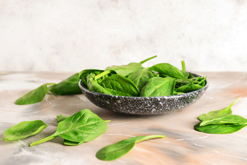 Plate with fresh spinach on table